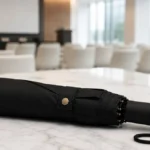 payung lipat otomatis premium hitam di meja marmer seminar room
