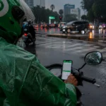 Pengendara Ojek Online Memakai Jas Hujan di Jakarta